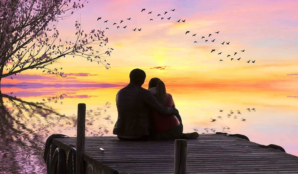 Paar sitzt auf Bootssteg im Sonnenuntergang