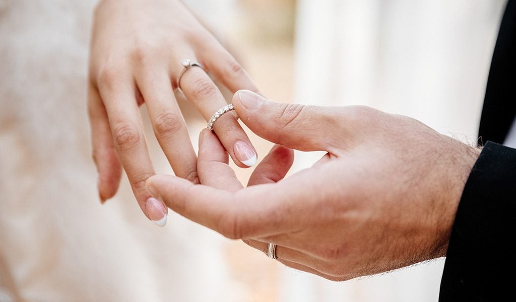 Groom puts wedding ring on brides left hand